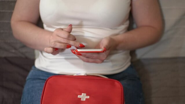 a woman holds a smartphone in her hand. a woman writes a message to a doctor. a woman and a first aid kit.slow motion video.close-up. High-quality frames in Full HD format