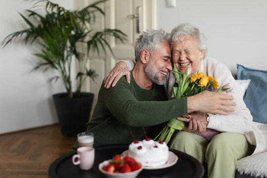 Mature man visiting his senior mother at her apartment.