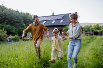 Family walking near their house with photovoltiacs panels on the roof.