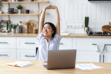 Relaxed young woman freelancer or student stretching hands and body taking break workplace in home, smiling