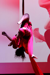 Acrobatic aerial dance dancer on red fabrics.