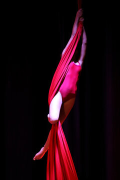 Acrobatic aerial dance dancer on red fabrics.