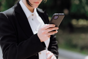 A girl uses a mobile phone while walking on the street in spring. The concept of working on the Internet.