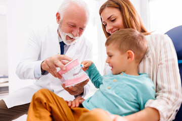 Dentist educating child patient about teeth brushing techniques