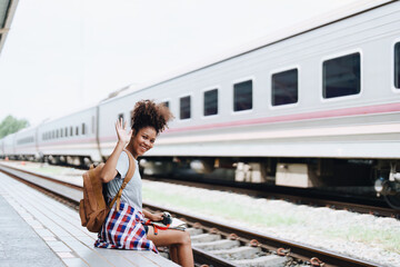 Asian teenage girl african american traveler dressed in casual wear holding map and searching right direction of route setting while waiting for a train at the station.