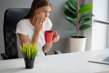 Unhappy young worker suffering from aching teeth in the office