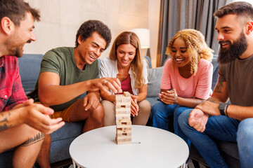 Friends having fun playing block stacking and removing balance game