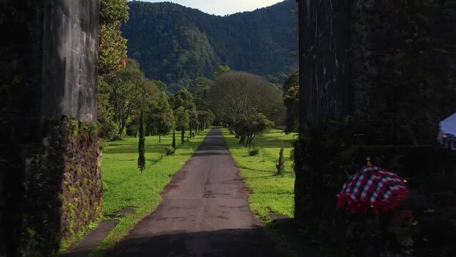Drone flying through beautiful Balinese gate towards mountains and jungle view. Famous tourist place in Indonesia, Bedugul. Handara gate in Bali