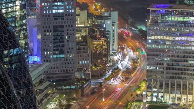 Aerial view of traffic on Al Saada street in financial district night timelapse in Dubai, UAE. Illuminated skyscrapers and glowing windows in office towers from above.