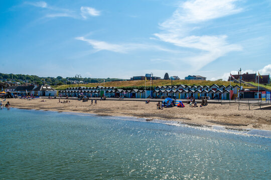People and beach huts on Swanage Beach- Swanage, UK.