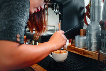barista making coffee, the hand of a barista with a wooden spoon making or preparing coffee foam in a cup of coffee.
