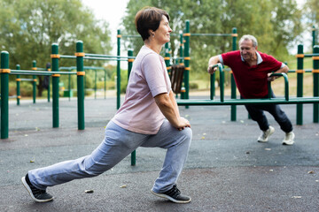 Aged woman practicing gymnastics in open-air sports area