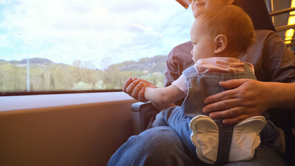 Toddler daughter with mother together ride on journey by train, close-up