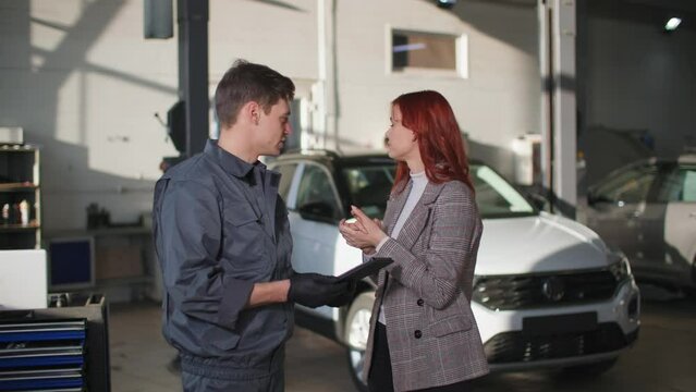 young frustrated female client communicates with a male technician about a breakdown of a vehicle engine in a car service