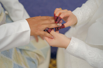 Obraz na płótnie Canvas Malay wedding groom bolstering gold ring on bride's finger