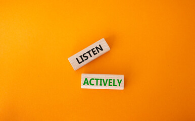 Listen actively symbol. Wooden blocks with words Listen actively. Beautiful orange background. Business and Active listening concept. Copy space.