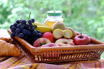 beautiful summer still life, fruits, grapes, peaches, apples, croissants, green trees in the background, concept picnic in nature, summer vacation, healthy eating