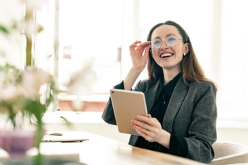 Accountant with glasses in a jacket woman uses a laptop computer workplace employee in the office. Happy young designer architect assistant online job.