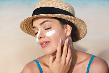 Beautiful Young woman with sun cream on face. Female in hat applying moisturizing lotion on skin.Skin care. Sun protection. Suntan