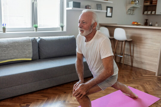 Shot of a relaxed mature man practicing yoga inside of home, during the day.