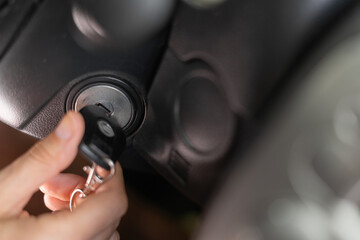 Hand putting car key to the keyhole or ignition, woman starting car.