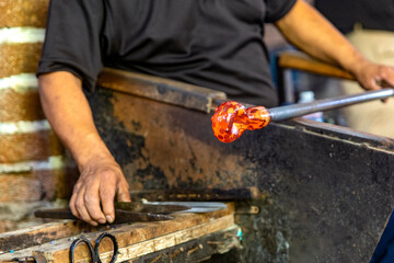 Craftsman cutting and blowing the glass in fusing temperature to make a bottle with the old...