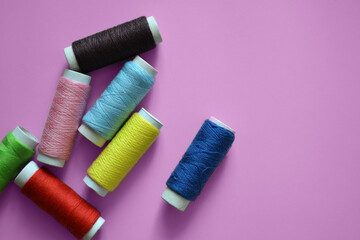 spools of thread on a pink background, a banner for an atelier, tailoring, sewing threads, photos for a textile factory