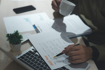 Business man hand writing schedule, checking event planning on calendar with laptop computer on desk.