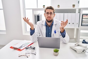 Hispanic man with beard wearing doctor uniform and stethoscope shouting and screaming loud to side...