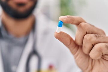 Obraz premium Young hispanic man doctor holding pill at clinic