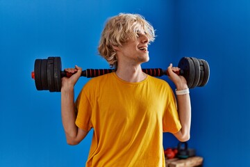 Young blond man smiling confident using weight training at sport center