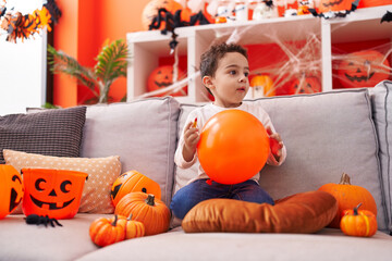 Fototapeta premium Adorable hispanic boy having halloween party holding balloon at home