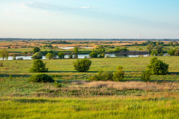Picturesque landscape of a river valley with a meadow and a lake, reeds and trees on a summer sunny day. Nature of Ukraine © Vlad Kazhan