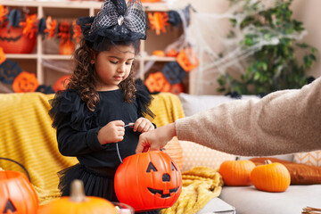 Adorable hispanic girl having halloween party receiving sweets at home
