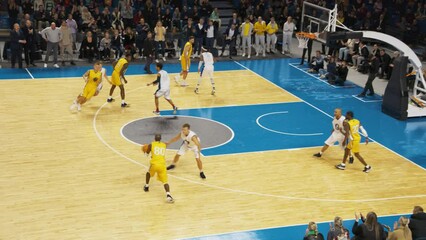 Basketball Match in an Arena. Team Passing Ball Between Teammates, Player Scoring a Two-Point Goal From a Distance to Secure a Victory. Crowd is Applauding and Celebrating Together with Basketballers