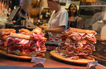 Fototapeta premium Spanish street food, Spanish sandwiches with sliced iberian cured ham jamon, bocadillo in showcase