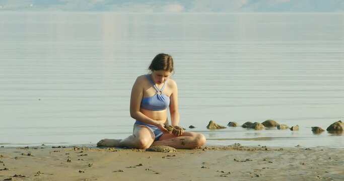 A young girl is playing on sand on the Beach on Rab Island, Croatia
