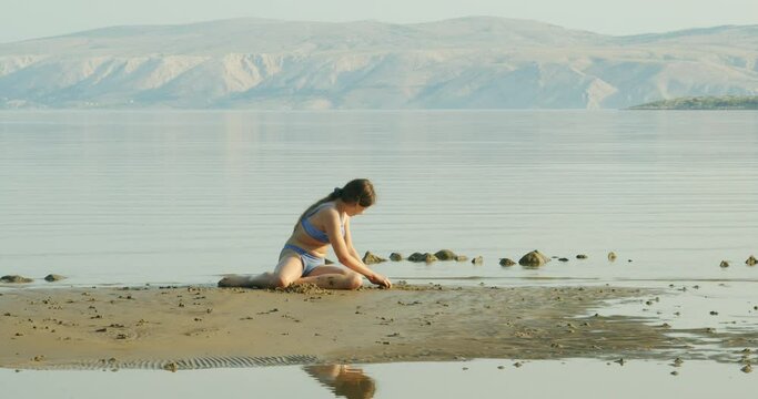 A young girl is playing on sand on the Beach on Rab Island, Croatia