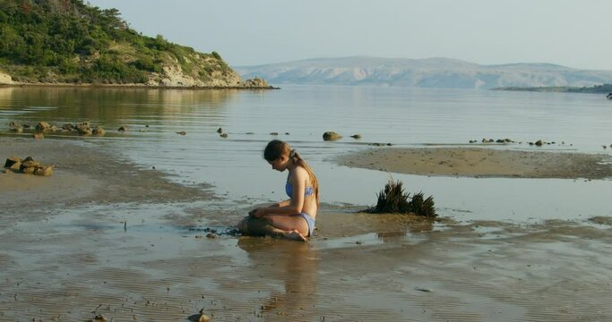 A young girl is playing on sand on the Beach on Rab Island, Croatia