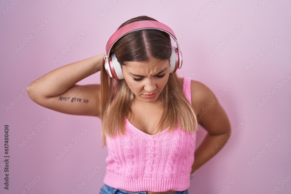 Canvas Prints Young blonde woman listening to music using headphones suffering of neck ache injury, touching neck with hand, muscular pain