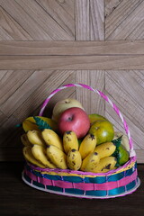 tropical fruit in a rattan basket. bananas, oranges, red apples, pears, and star fruit.