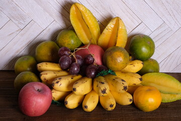 tropical fruit on wooden table. banana, orange, star fruit, red grapes, apples. buah tropis. 