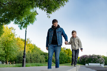 Caucasian bearded man with his little son walking in park holding hands