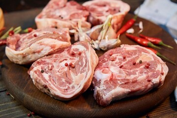Pieces of raw meat, hot pepper and garlic lie on a wooden cutting board. Raw food for cooking.