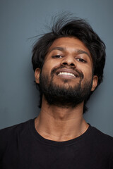 Fototapeta premium A man in a black t-shirt on a gray background with a smile