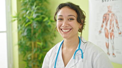Young beautiful hispanic woman doctor smiling confident standing at clinic
