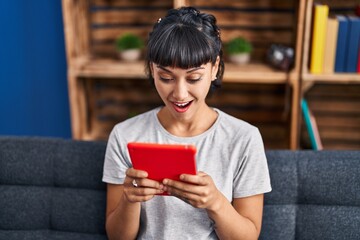 Young woman using touchpad sitting on sofa at home