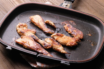 chicken steak on a black teflon pan on wooden table. non stick pan.
