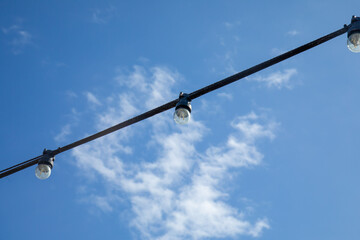 String of outdoor street lights in the bright blue sky in summer