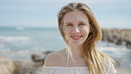 Young blonde woman tourist smiling confident standing at beach